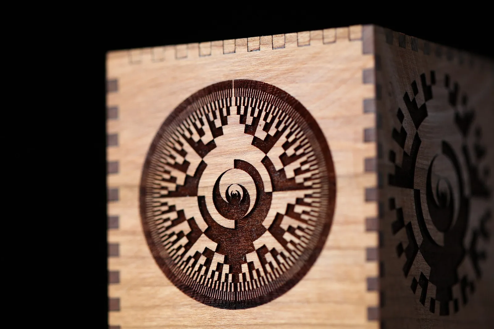 A finger-jointed cherry wood box with a dense circular pattern laser-engraved on each side