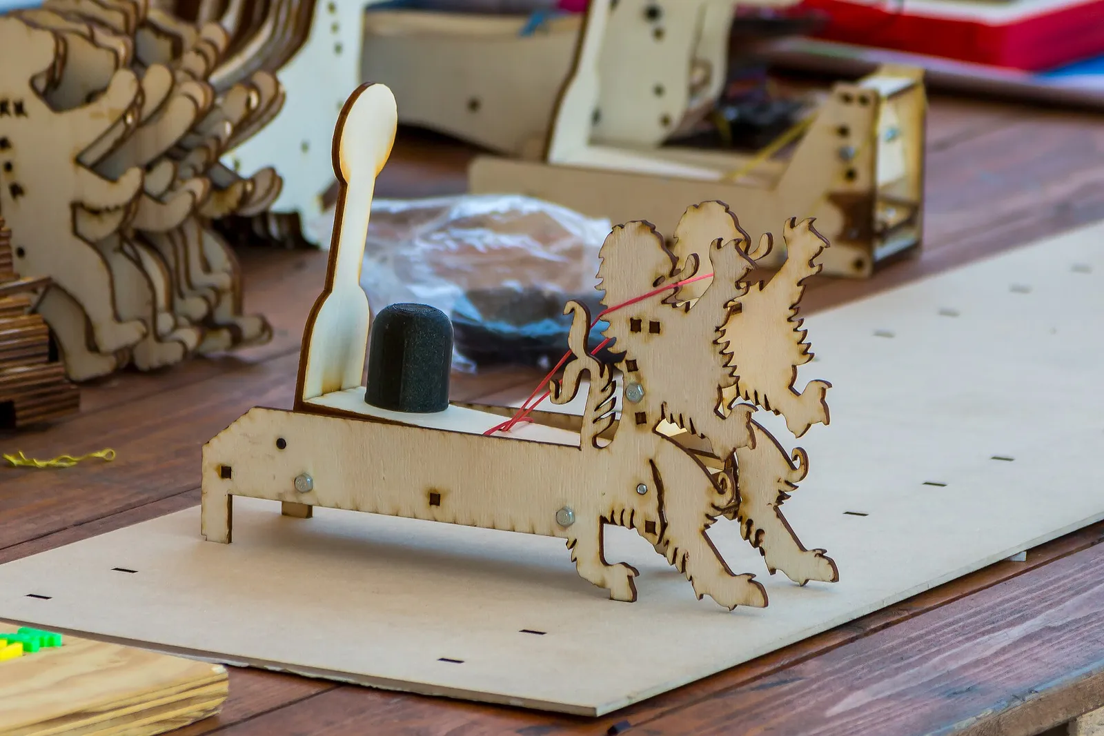 A small catapult built from laser-cut plywood parts, decorated with two rampant lions