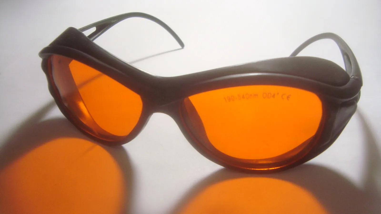 Orange-tinted laser safety goggles marked with their wavelength range and optical density