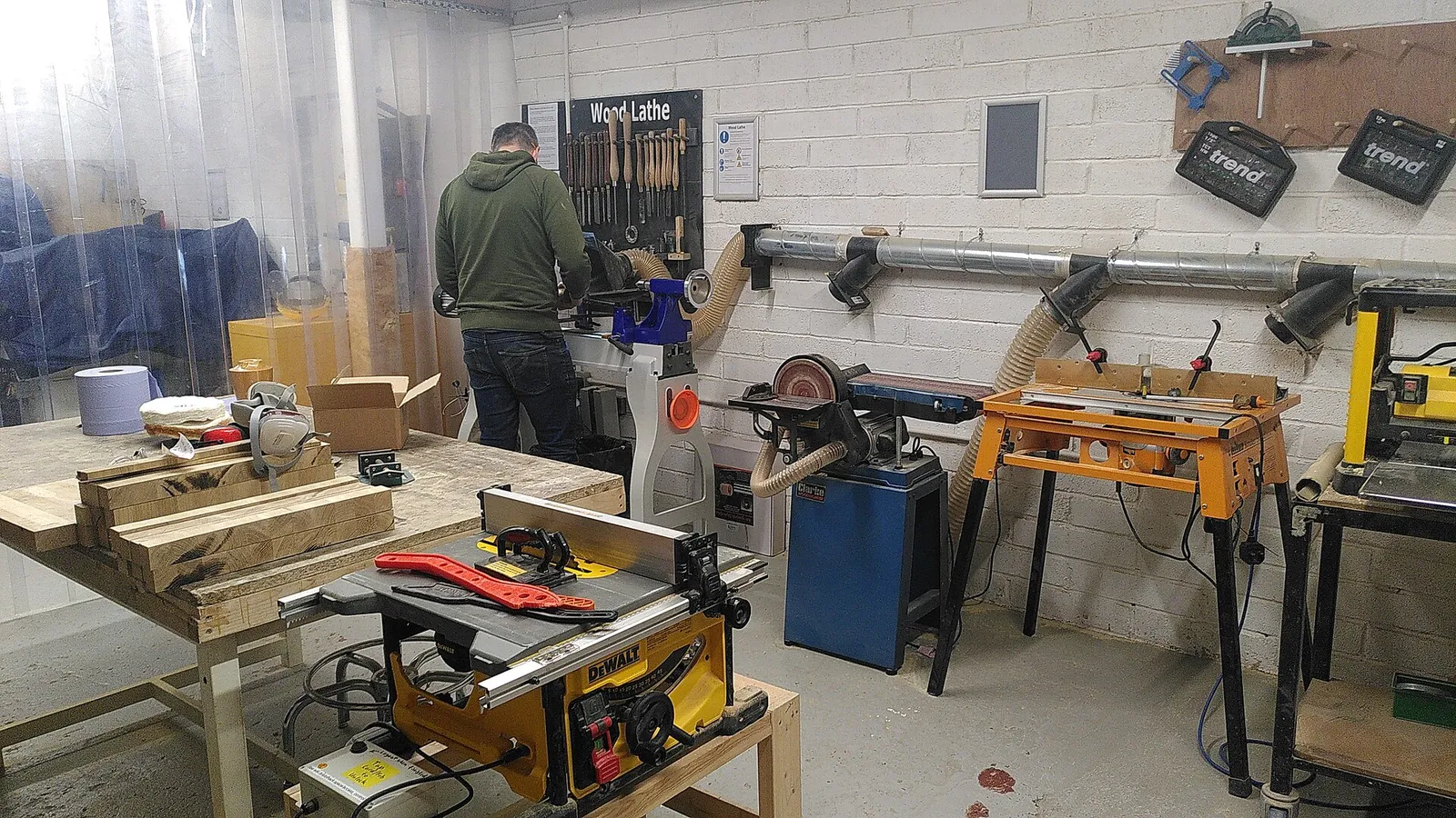 The wood workshop at Bristol Hackspace with a table saw, band saw and other machines along the walls